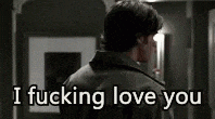 a man in a black jacket is standing in a hallway and says i fucking love you .