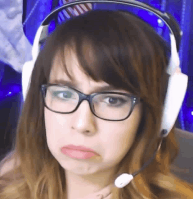 a woman wearing glasses and headphones with a microphone making a sad face .
