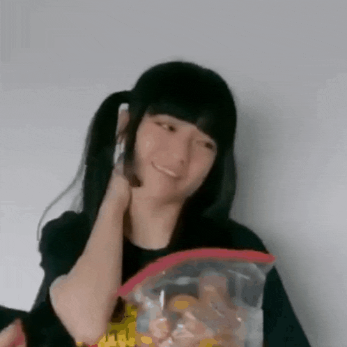 a girl with pigtails is holding a bag of chips .