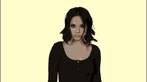 a woman in a black shirt is looking at the camera with a yellow background