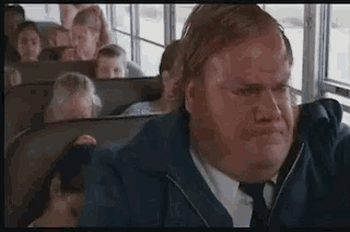 a man in a suit and tie is sitting on a school bus with other people .