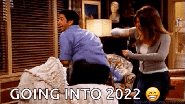 a man and a woman are standing next to each other on a bed with the words `` going into 2022 '' written above them .