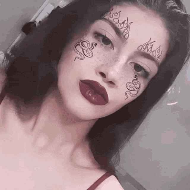 a woman has a tattoo of a snake on her forehead