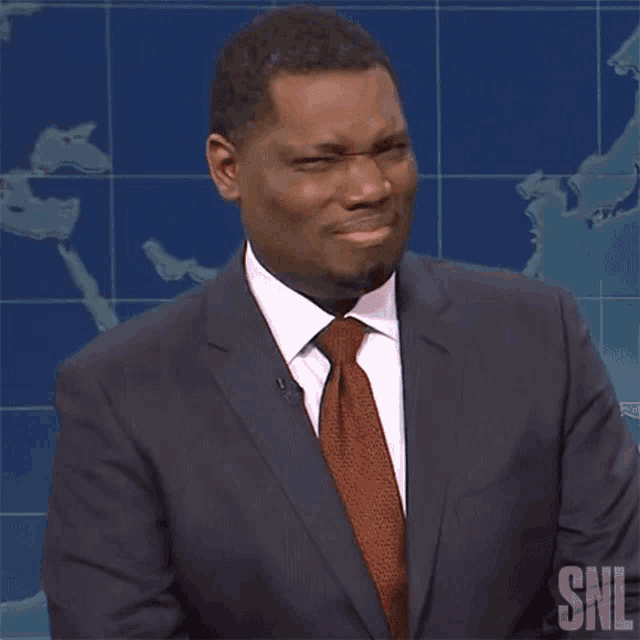 a man in a suit and tie with the snl logo on the bottom