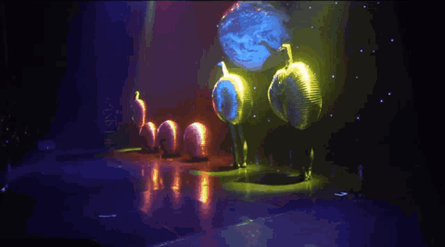 a group of people standing on a stage with a globe projected on the wall behind them