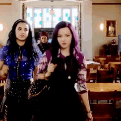 two girls with purple hair are walking in a room .