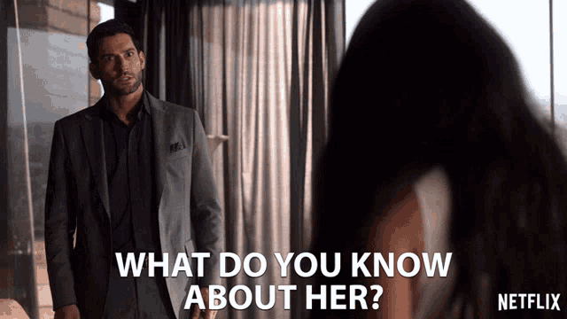 a man in a suit stands in front of a woman and asks what do you know about her