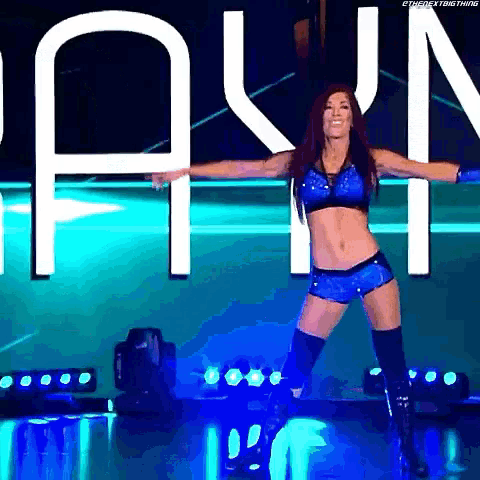 a female wrestler is dancing on a stage in front of a large screen .