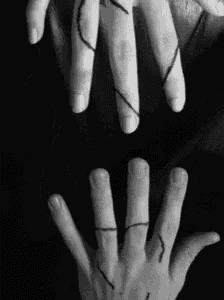 a black and white photo of a person 's hands with a string between them .