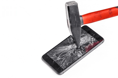 a hammer is smashing a broken cell phone .