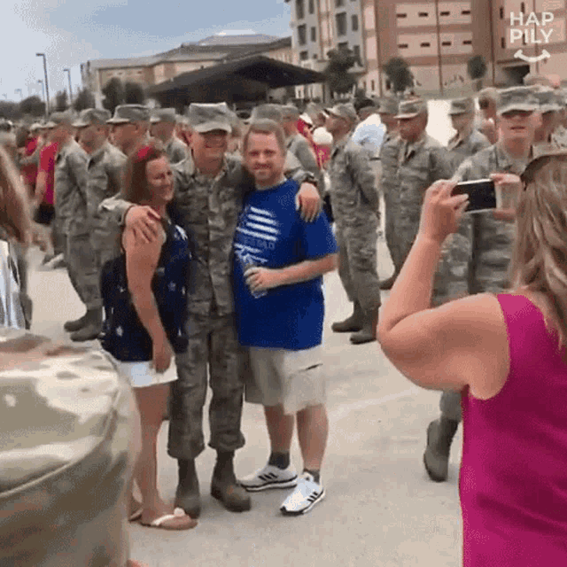 a group of soldiers are posing for a picture with a woman taking a picture .
