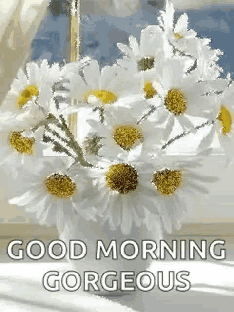 a bouquet of daisies in a vase on a table with the words `` good morning gorgeous '' .
