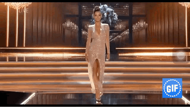 a woman in a dress is walking down a staircase with a gif icon in the corner