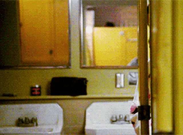 a bathroom with two sinks and a mirror with a yellow curtain