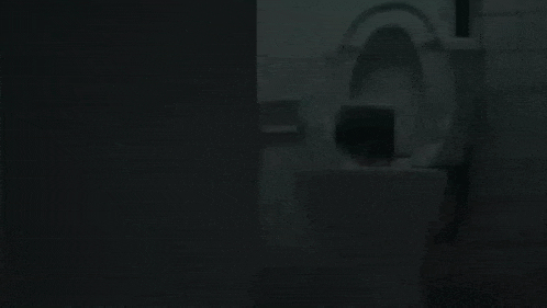 a hand is sticking out of a sink in a dark bathroom