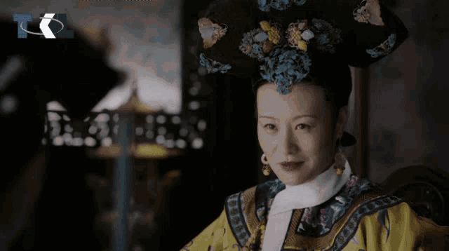 a woman in a yellow and gold dress with a white collar and earrings