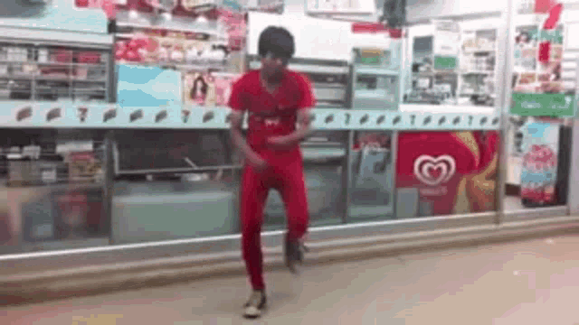 a man in a red shirt is dancing in front of a store .