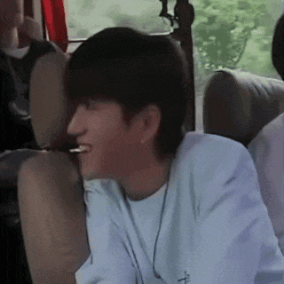 a young man is sitting in the back seat of a car smoking a cigarette .