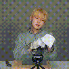 a man is sitting at a table holding a piece of paper and a pen .