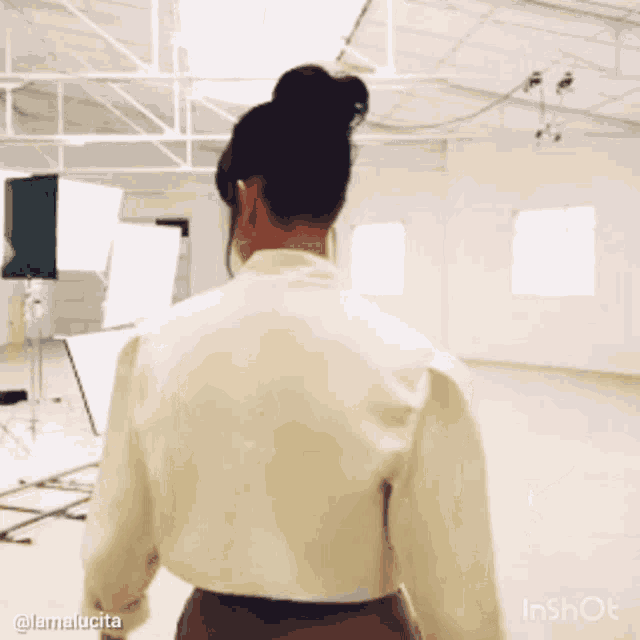 a woman in a white shirt and brown skirt is standing in a room