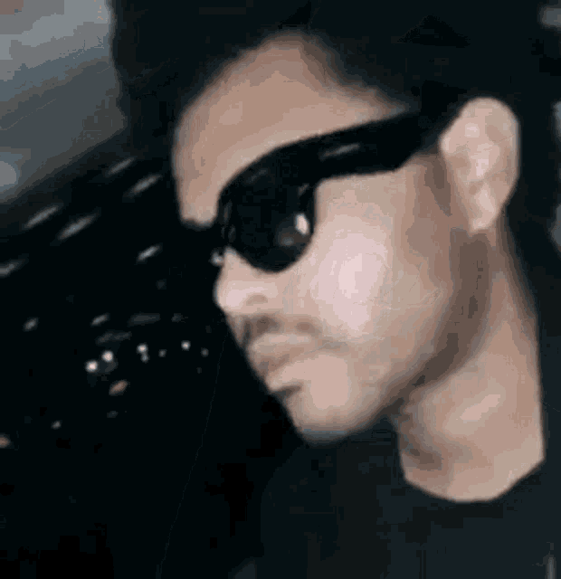 a man wearing sunglasses and a black shirt is looking to the side .