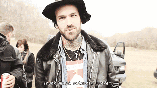 a man wearing a hat and a leather jacket says " trunk muzik returns fucker "