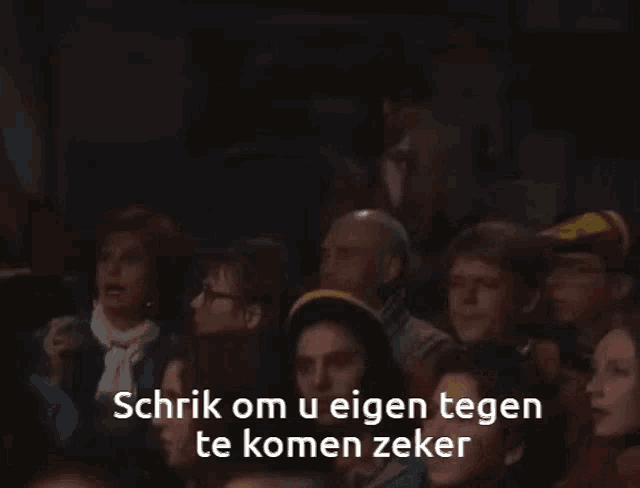 a man in a suit and tie is standing in front of a sign that says schrik om u eigen tegen