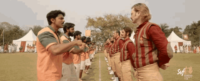 a group of men standing on a field with a syfy logo on the bottom