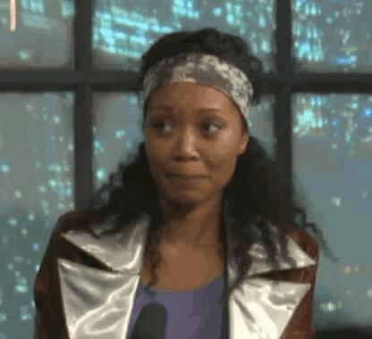 a woman wearing a headband and a jacket is looking at the camera