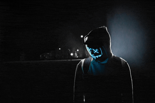 a person in a hoodie with a neon mask on