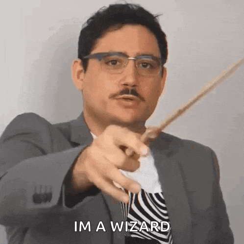 a man in a suit and tie is pointing with a wand and saying `` im a wizard '' .