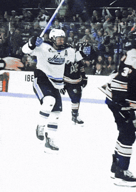 a hockey player in a maine jersey holds up a bat