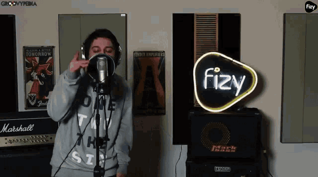 a man singing into a microphone in front of a fizzy sign