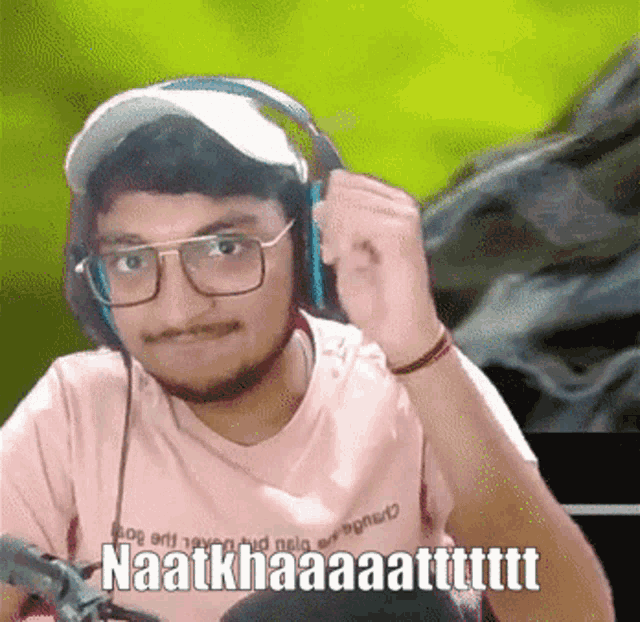 a man wearing headphones and a pink shirt that says naatkhaaaatttttt