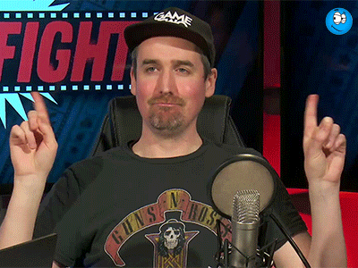a man wearing a guns n roses shirt is sitting in front of a microphone with his fingers in the air