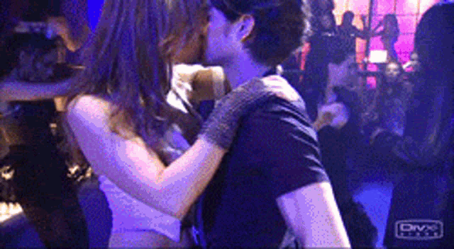 a man and a woman are kissing in a club with divx written on the bottom