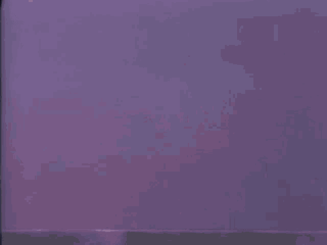 a close up of a puppet with a red hat on a purple background .