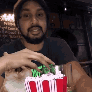a man with a beard is eating popcorn in front of a sign that says super 's february