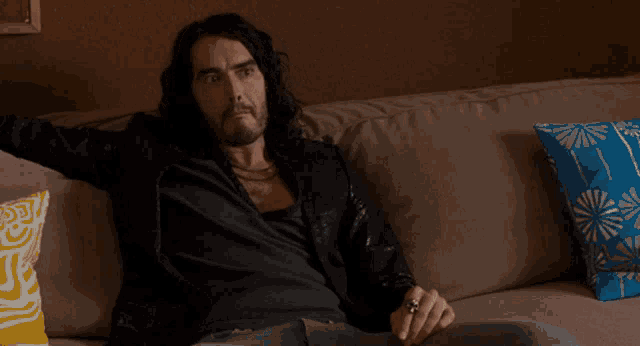 a man sitting on a couch with a remote control in his hand