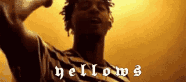 a man in a striped shirt is standing in front of a yellow background with the word hellow written on it .