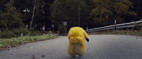 a small yellow stuffed animal is standing on the side of a road