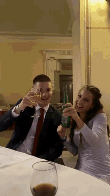 a man and a woman toasting with a bottle of heineken