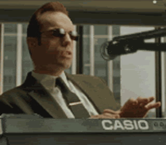 a man in a suit and tie is playing a casio keyboard ..