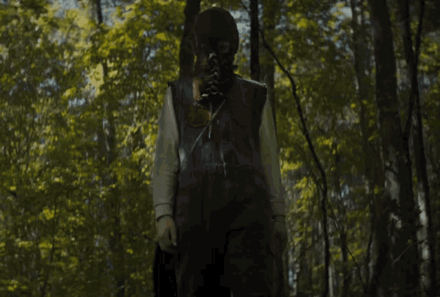 a person wearing a mask and overalls is walking through a forest