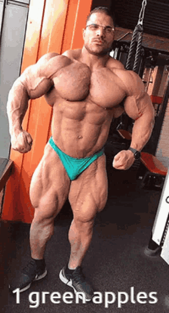 a muscular man in a green underwear is standing in a gym with the caption 1 green apples