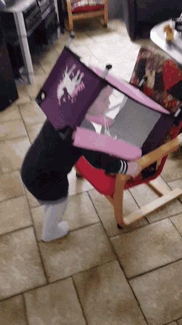 a child is playing with a purple and pink box that says unicorn