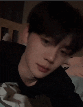 a close up of a young man laying on a bed with his eyes closed