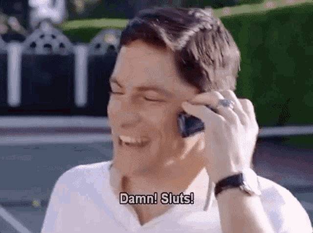 a man is laughing while talking on a cell phone and says `` damn ! sluts ! ''