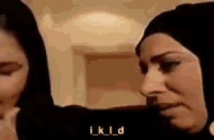 two women wearing hijabs are standing next to each other and looking at each other .