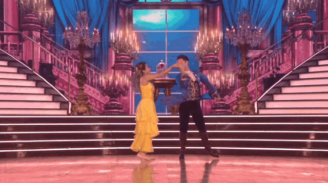 a man and a woman are dancing on a stage in front of stairs